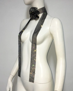 Détail d'une cravate en résille strass noire avec une fleur de camélia 3D sur mannequin