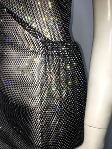 Gros plan sur une robe en résille noire ornée de strass multicolores brillants sur mannequin