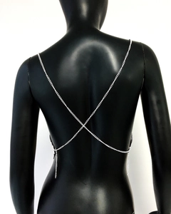 Detail of silver metal back chain with intricate X-shaped cross design on black mannequin