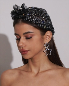 Gros plan d'un bandeau en strass noirs et de grandes boucles d'oreilles étoiles