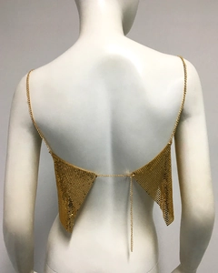 Détail d'un haut à paillettes dorées avec dos nu à chaîne et scintillement métallique