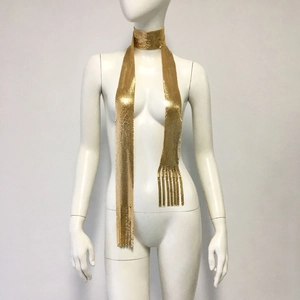 Close-up of golden metallic mesh scarf with tassel fringe on a white mannequin