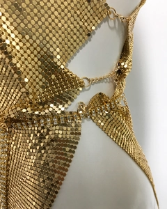 Close-up of golden metallic sequin mesh fabric with rhinestone trim details on a dress