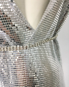 Detail of silver sequin mesh dress with shimmering texture and rhinestone waist chain