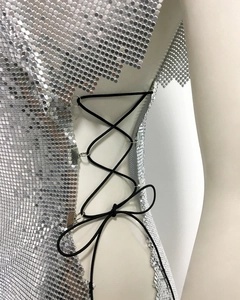 Détail de sequins métalliques argentés avec laçage latéral et anneaux sur la robe sexy