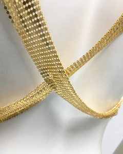 Detail of golden metal sequin mesh fabric with metallic sheen on a white mannequin
