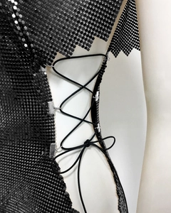 Détail de robe à paillettes noires avec laçage latéral et œillets métalliques argentés