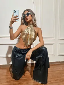 Detail of gold metal mesh halter top with diamond hem and black faux leather pants