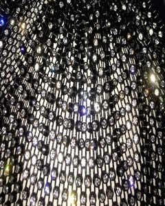 Macro close-up of high-elasticity black mesh fabric with sparkling white rhinestones