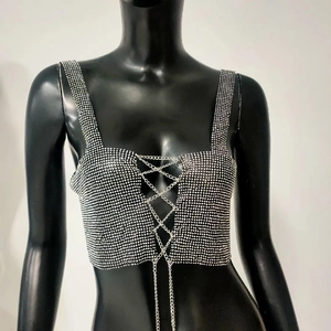 Close-up of sparkling rhinestone crop top with criss-cross metal chain details