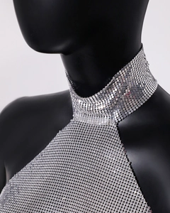 Close-up of sparkling silver sequin halter top with metallic mesh texture and high neck