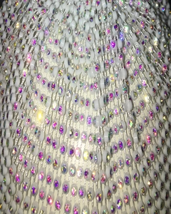 Macro detail of white mesh head mask featuring iridescent rhinestones on woven beads