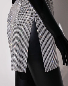 Close-up of sparkling silver rhinestone mesh dress with side slit and metal chain detail