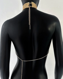 Détail d'un haut à paillettes dorées avec tour de cou en maille et chaînes de corps superposées
