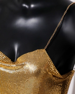 Détail d'un haut à paillettes dorées en maille métallique avec fines bretelles
