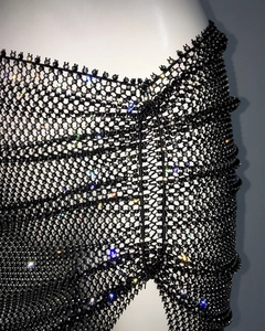 Close-up detail of black fishnet fabric with sparkling rhinestones on mesh intersections
