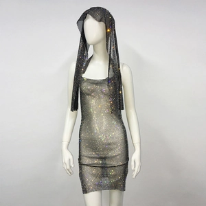 Dettaglio dell'abito corto in rete di strass scintillanti e copricapo con paillettes