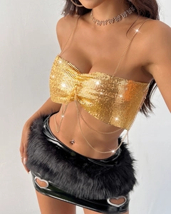 Detail of gold metal mesh crop top with chain straps and black PVC skirt with fur trim