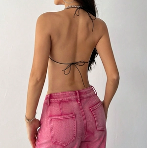 Détail du haut bandeau noir avec laçage au dos et pantalon en denim délavé rose