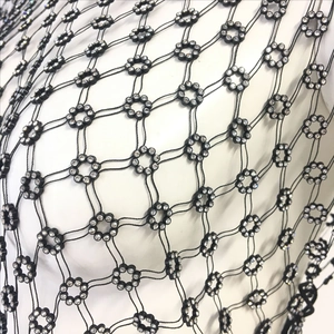 Detail of fishnet top with rhinestone floral clusters and intricate woven black cords