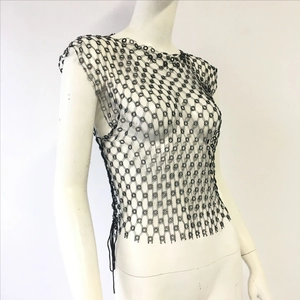 Macro detail of black beaded fishnet vest featuring intricate floral lattice handwork