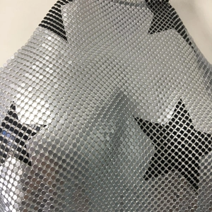 Macro shot of silver metal sequins with black star patterns and mesh stitching detail