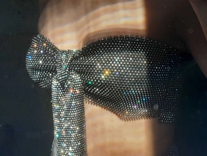 Detail of shimmering silver rhinestone bow tube top featuring a dense crystal mesh texture
