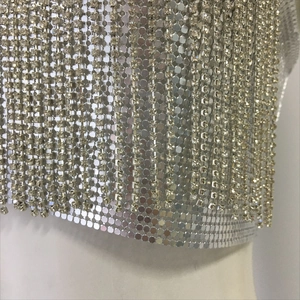 Detailed macro view of silver metal mesh halter top with shimmering rhinestone fringe tassels