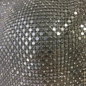 Macro shot of silver metallic mesh fabric with intricate sequin and rhinestone detailing