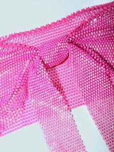 Macro detail of sparkly pink mesh fabric with high-density rhinestones and texture