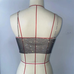 Detail of a sparkling rhinestone fishnet crop top with thin straps and silver crystals