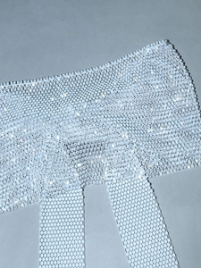 Detail shot of sparkling rhinestone mesh fabric with silver bow and crystal net texture