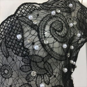 Detail of black lace camisole featuring intricate embroidery, pearls, and rhinestones