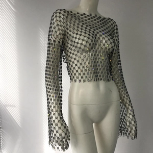 Detail of black rhinestone fishnet crop top with long sleeves and shimmering floral patterns