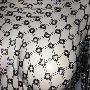 Detailed view of black fishnet top with sparkling floral rhinestones on white model