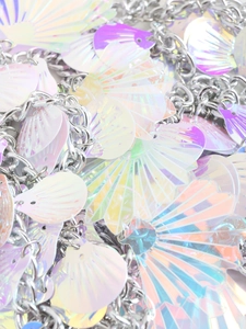 Macro view of iridescent shell sequins with silver metal chains on a sequin halter top