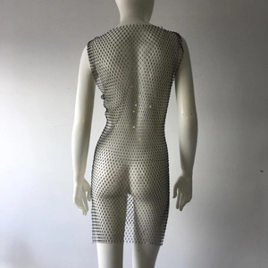 Macro shot of shimmering rhinestones on black fishnet mesh fabric of the mini dress