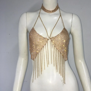Macro detail of gold metal chain body jewelry with rhinestones and tassel fringe on mannequin