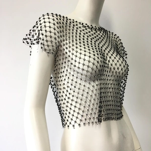 Macro detail of black fishnet mesh fabric featuring sparkling rhinestones on an inner top