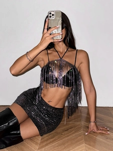 Detailed close-up of sparkling rhinestone fringe on a black halter top for parties