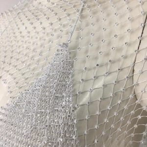 Macro shot of white diamond fishnet fabric with densely set rhinestones and fine mesh