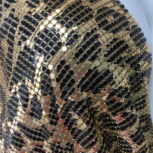 Detailed macro shot of gold and black leopard print metal sequin mesh fabric texture
