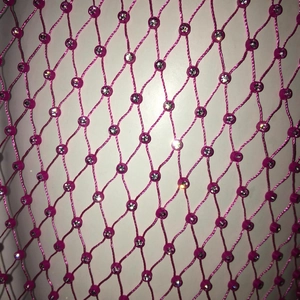 Vue rapprochée du tissu en résille rose avec des strass argentés et des détails en cristal