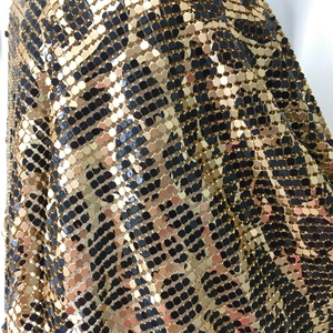 Macro shot of gold and black metal mesh fabric with a sequin leopard pattern