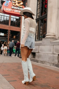 Streetstyle-Ansicht des weißen Mesh-Langarmtops mit Jeans-Shorts und Stiefeln kombiniert