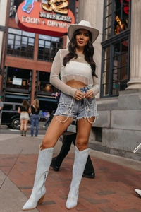 Detailaufnahme von beigem Mesh-Oberteil mit Strass und Perlenketten-Denim-Shorts