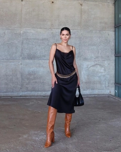 Robe longue noire satinée à col bénitier avec une ceinture chaîne dorée et bottes chic