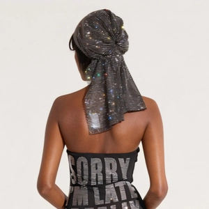 Detailed view of black pleated turban with colorful rhinestones and metallic finish