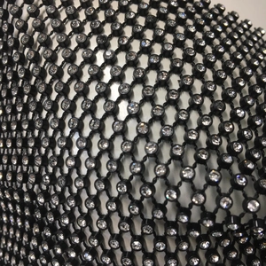 Dettaglio macro di strass scintillanti su tessuto a rete nero per abiti da festa