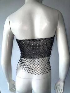Dettaglio del crop top in rete nera con strass e orlo irregolare scintillante